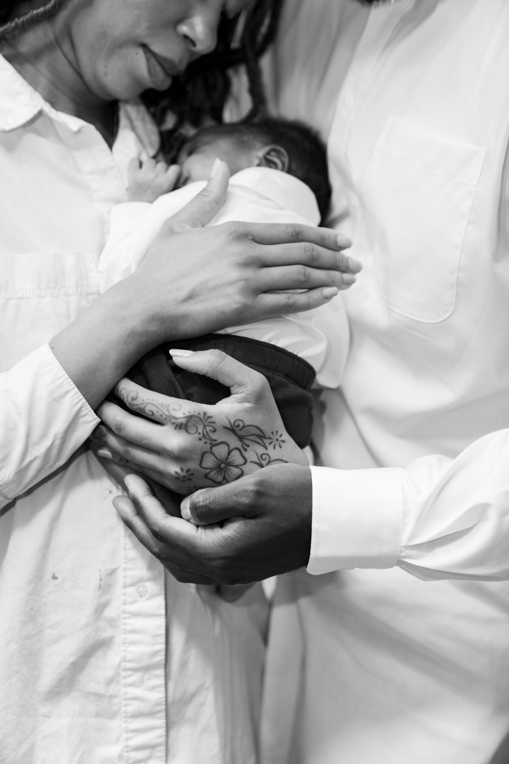 Couple standing with their new newborn baby, image with the baby and holding their newborn